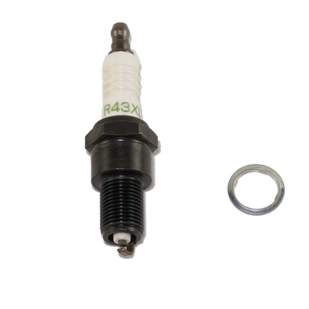 A black and white spark plug with green text reading "R43XLS" on it lying on its side against a white background.